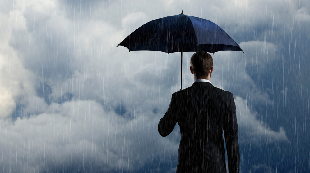 Business man under umbrella with heavy rain and storm clouds.