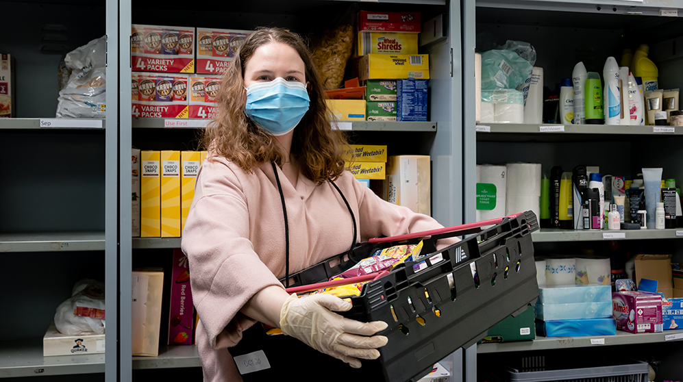 Foodbank worker carrying items and wearing a surgical mask