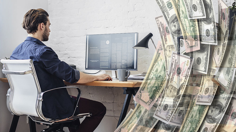 Man seated at desk using computer from a home office with vertical U.S. currency bills framing