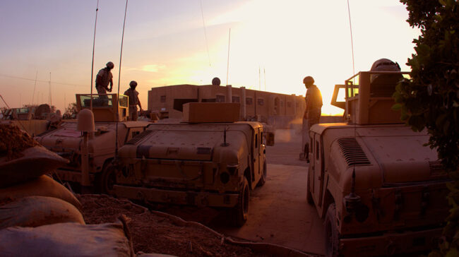 Desert sunset as soldiers exit military vehicles
