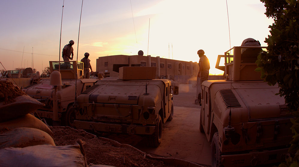 Desert sunset as soldiers exit military vehicles