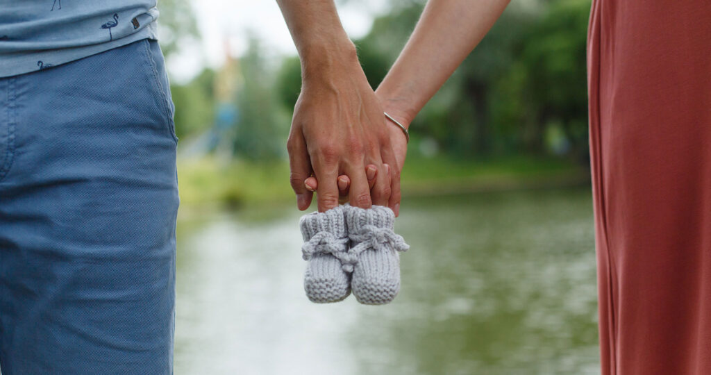 Two people holding hands with crochet baby slippers