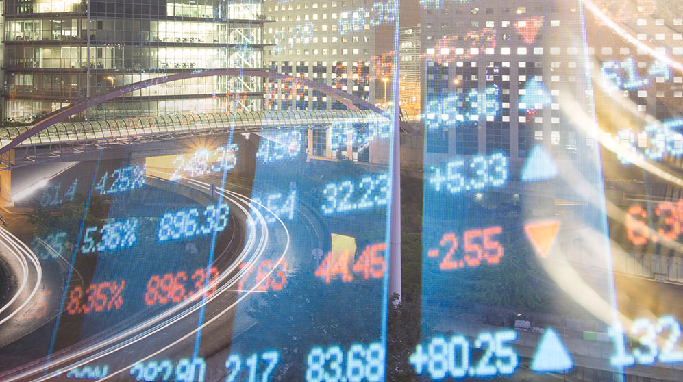 Financial markets digital numbers overlaid a nighttime cityscape.