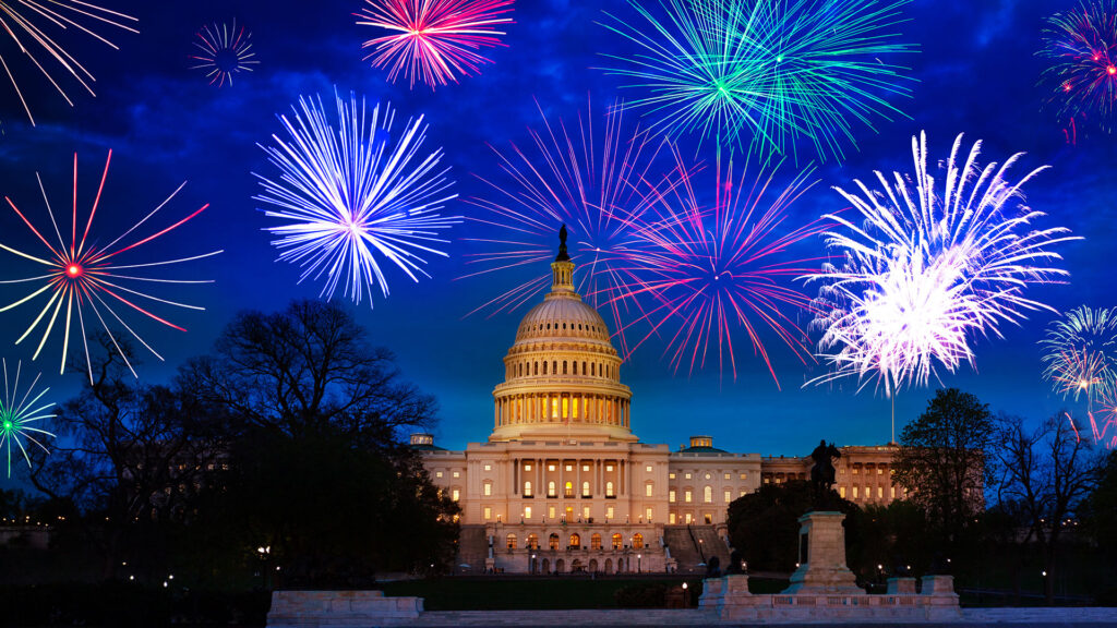 Illustrated fireworks over a lit U.S. Capitol building at dusk.