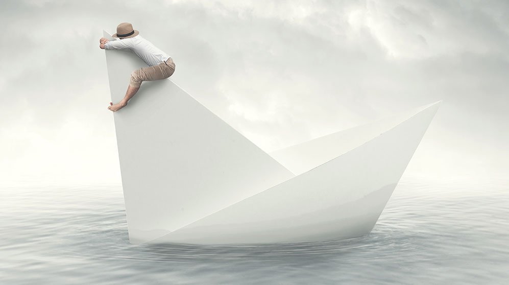 Drawing of a person holding onto the sail of a paper boat for dear life.