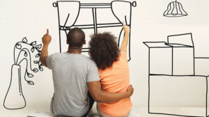 seated couple facing a wall and seemingly line drawing features of a home with fingers