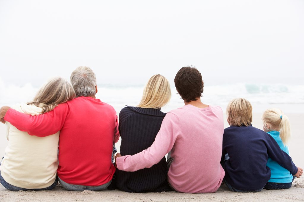 Three generations seated on beach.