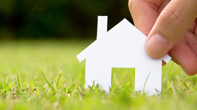 Photo of a hand holding a cardboard cutout of a house