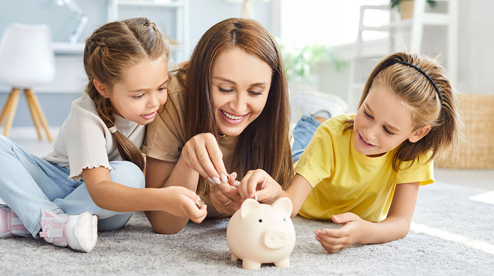 Photo of a mom and her two children putting money in a piggy bank